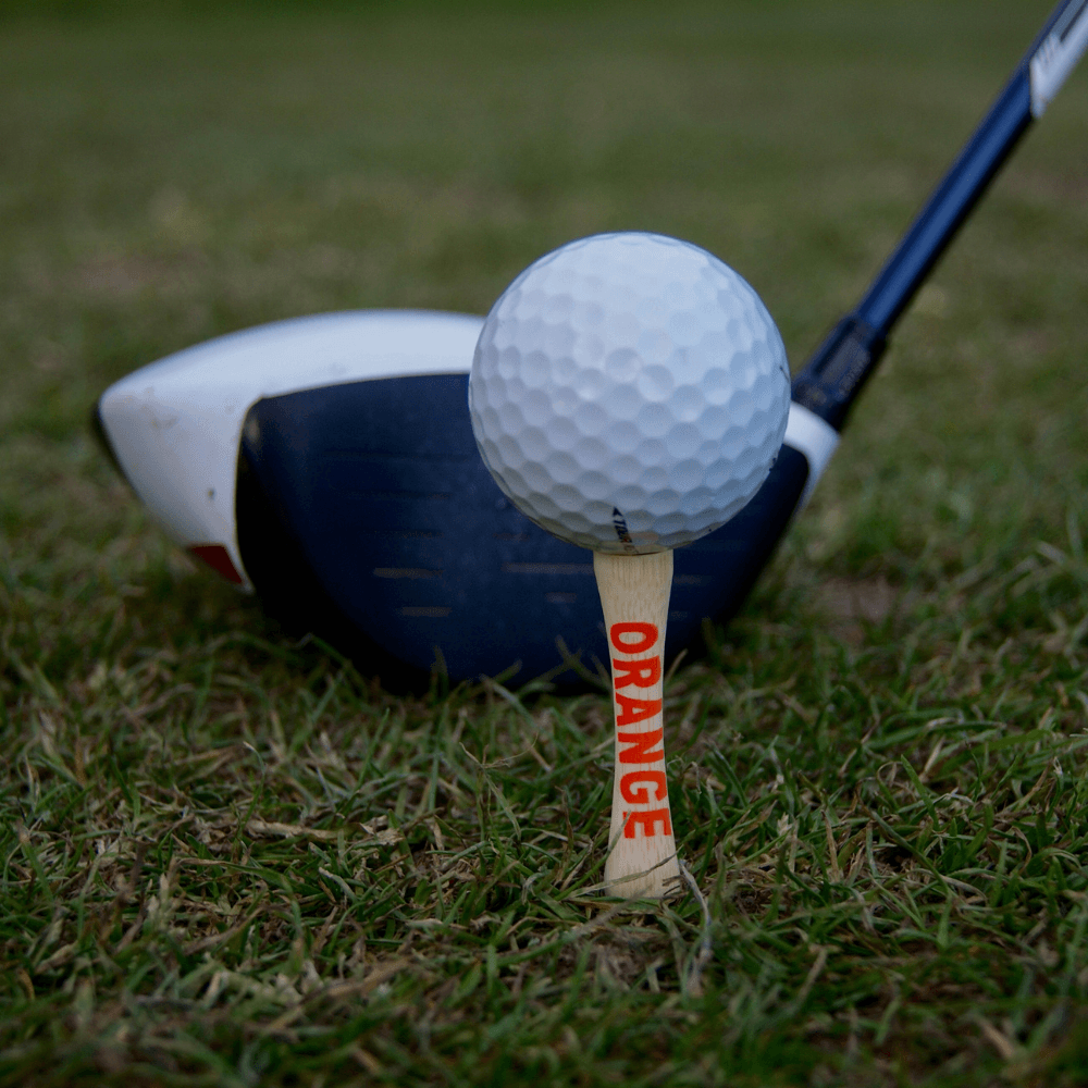 golf ball on top of orange bamboo golf tee